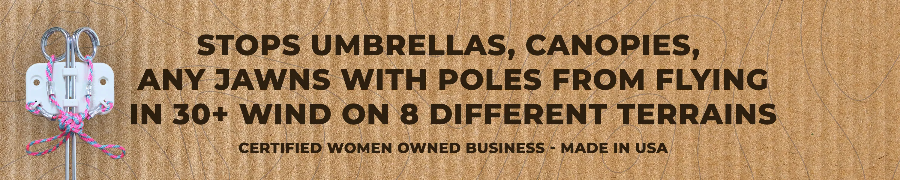 Metal device attached to wood with colorful rope ties, with text stating it stops umbrellas, canopies, and jawn poles from flying in 30+ mph wind on 8 terrains, and is made by a certified women-owned business in USA.