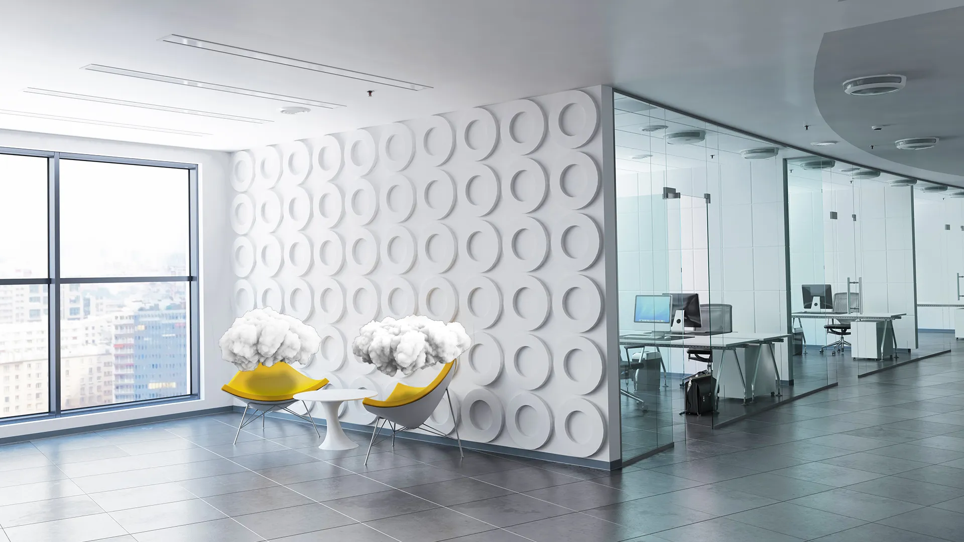 Bright modern office lounge with two yellow chairs and a white table, each chair topped with a cloud-shaped cushion, next to a large window and a glass-wall office area.
