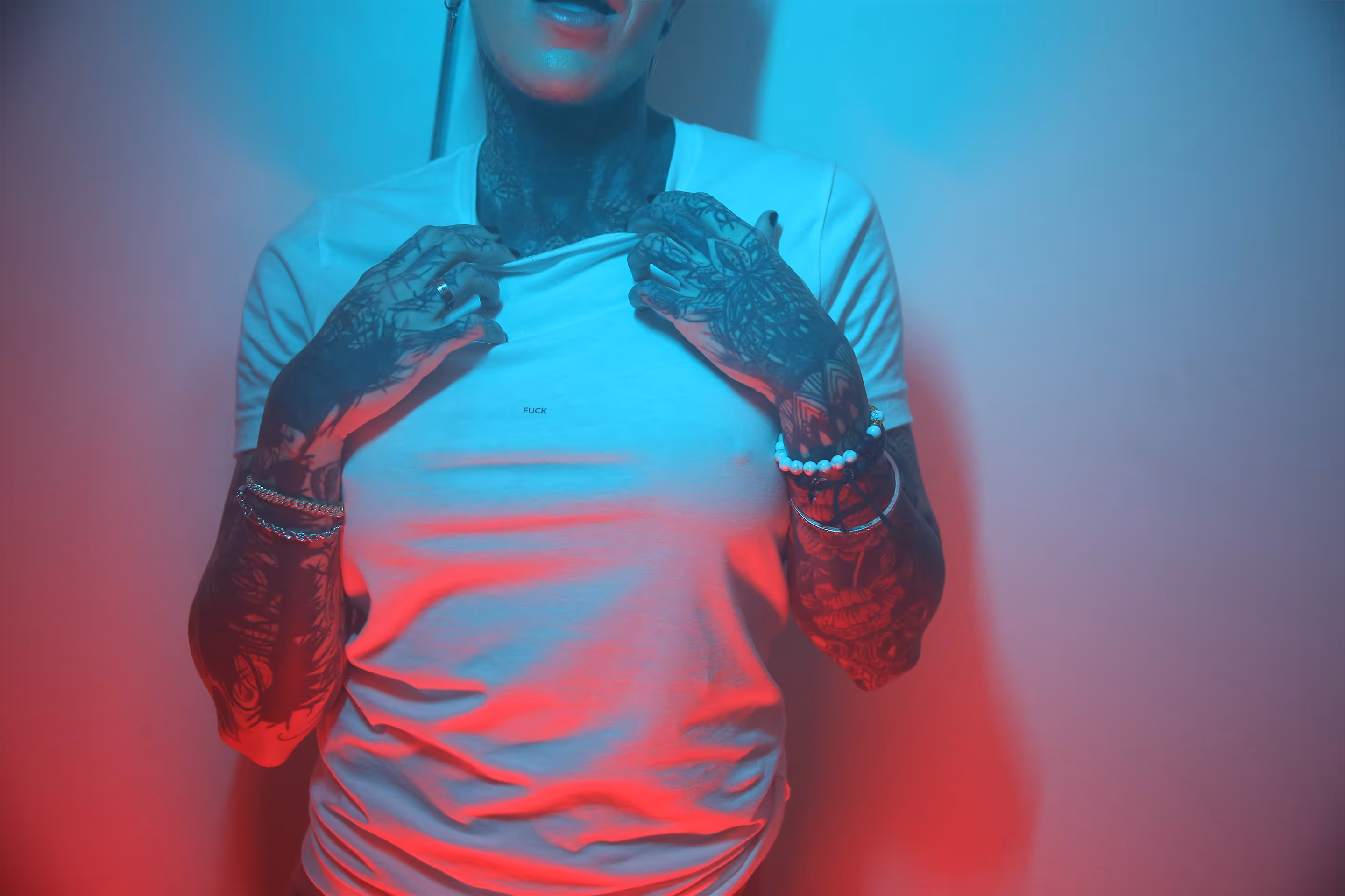 A black and white picture of a person holding a TKINK designer white t-shirt with a small printed "FUCK" over their head.